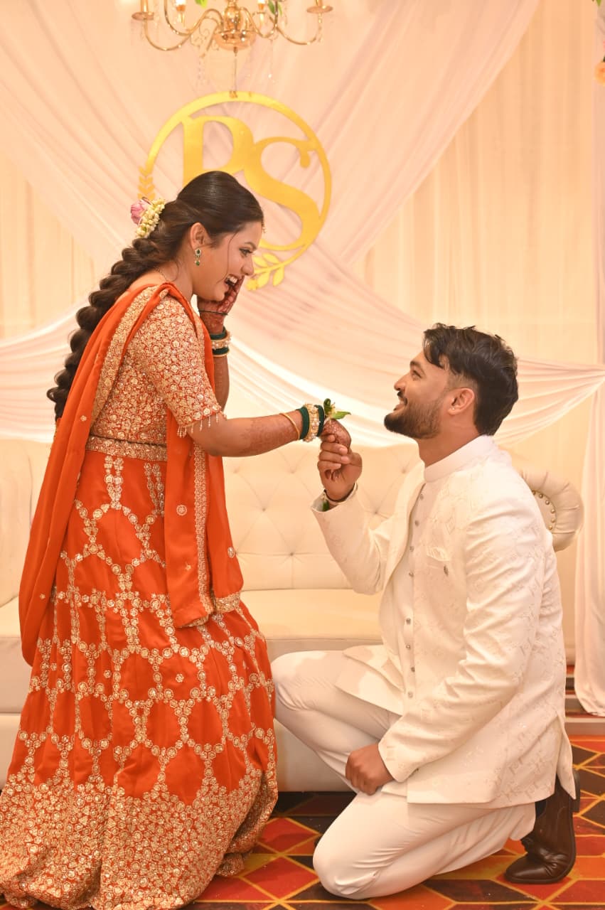 Ravi on one knee holding Soumya's hand, both laughing